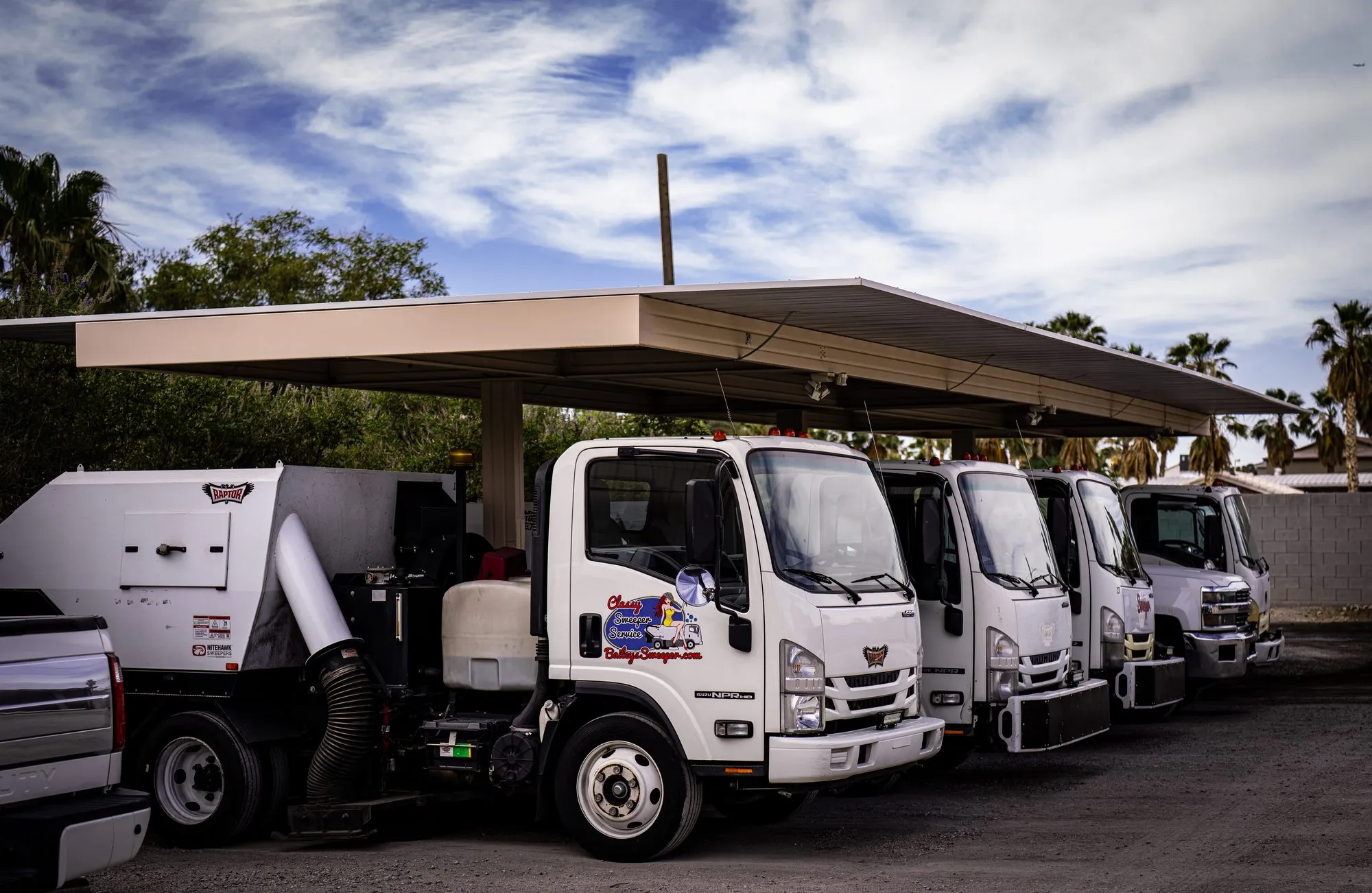 Bailey's fleet of Isuzu sweeper trucks lined up under the shade canopy at the yard