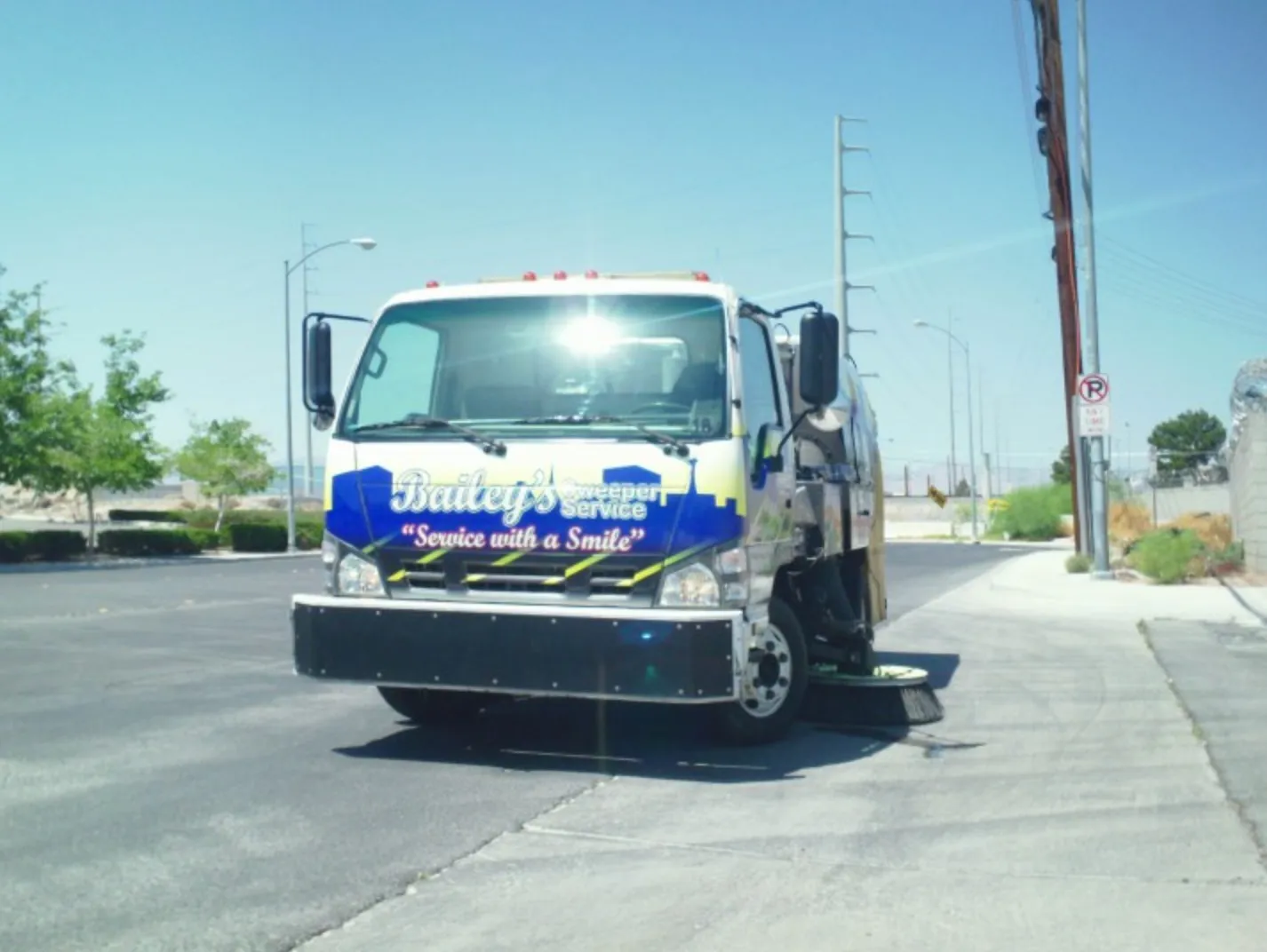 Front view of a Bailey's sweeper truck with the "Service with a Smile" tagline visible