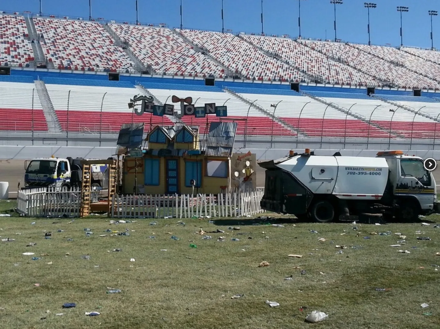 A Bailey's sweeper at the Speedway alongside an event stage installation, debris scattered across the infield