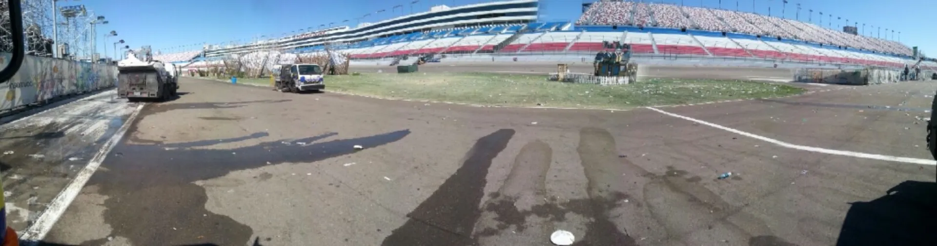Wide panorama of the Speedway grandstand with Bailey's sweeper trucks staged at the track