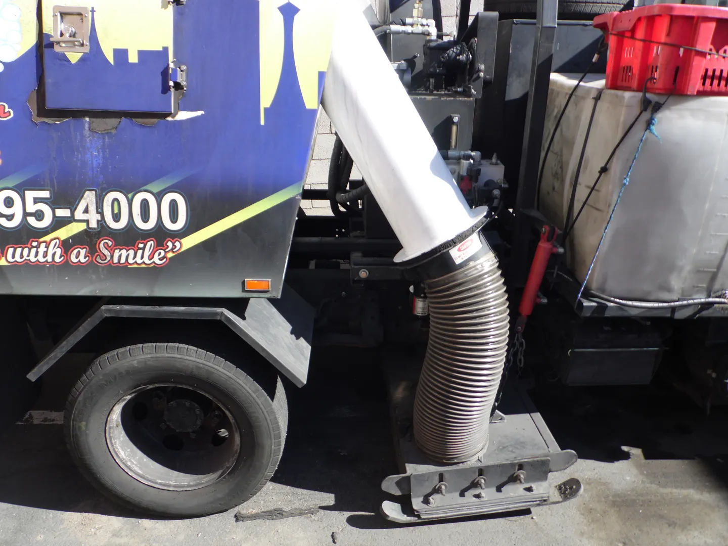 Close-up of a Bailey's sweeper's vacuum hose and tank with the "95-4000 with a Smile" branding visible