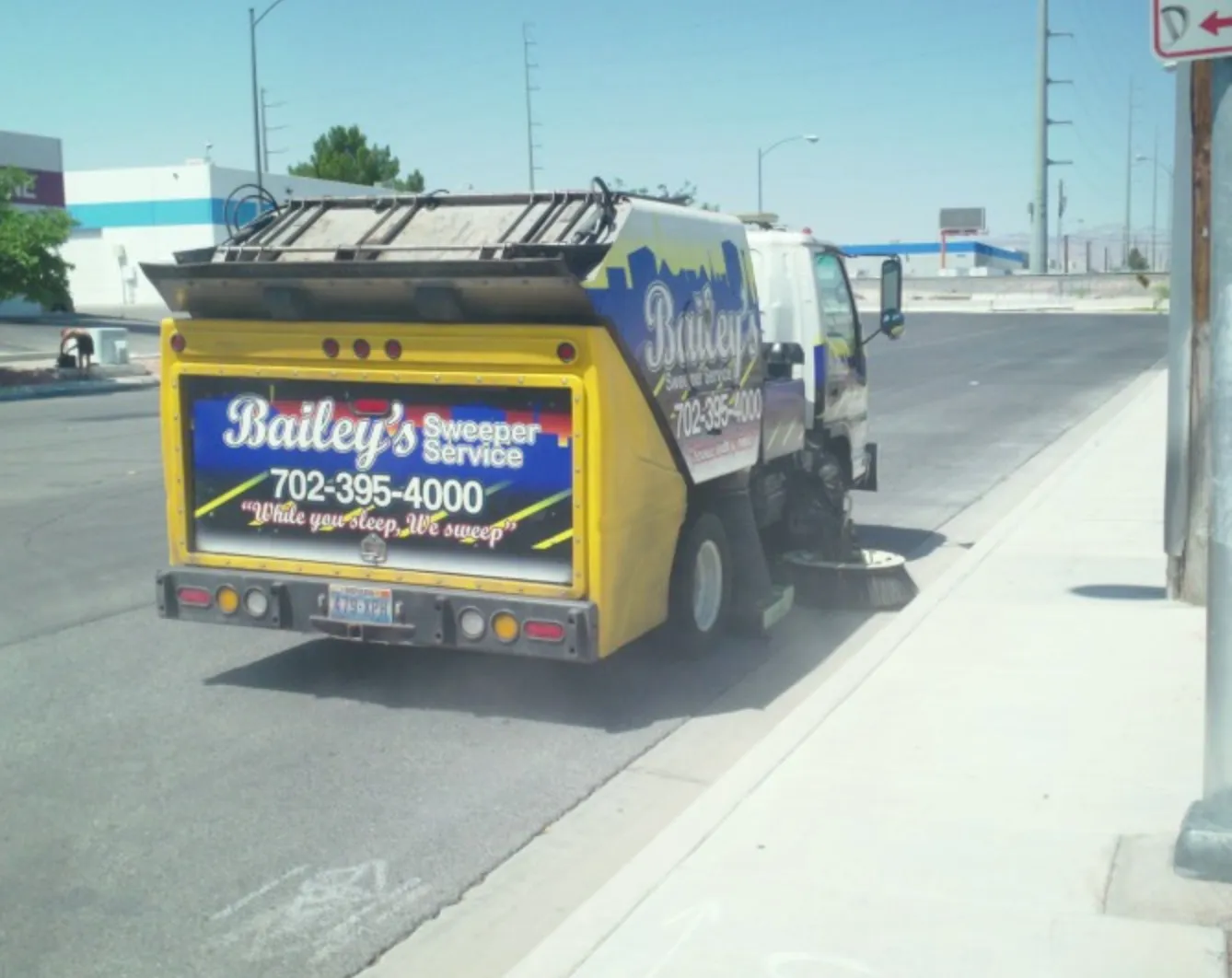 Rear of a Bailey's sweeper truck on a Vegas street showing the "While you sleep, We sweep" slogan