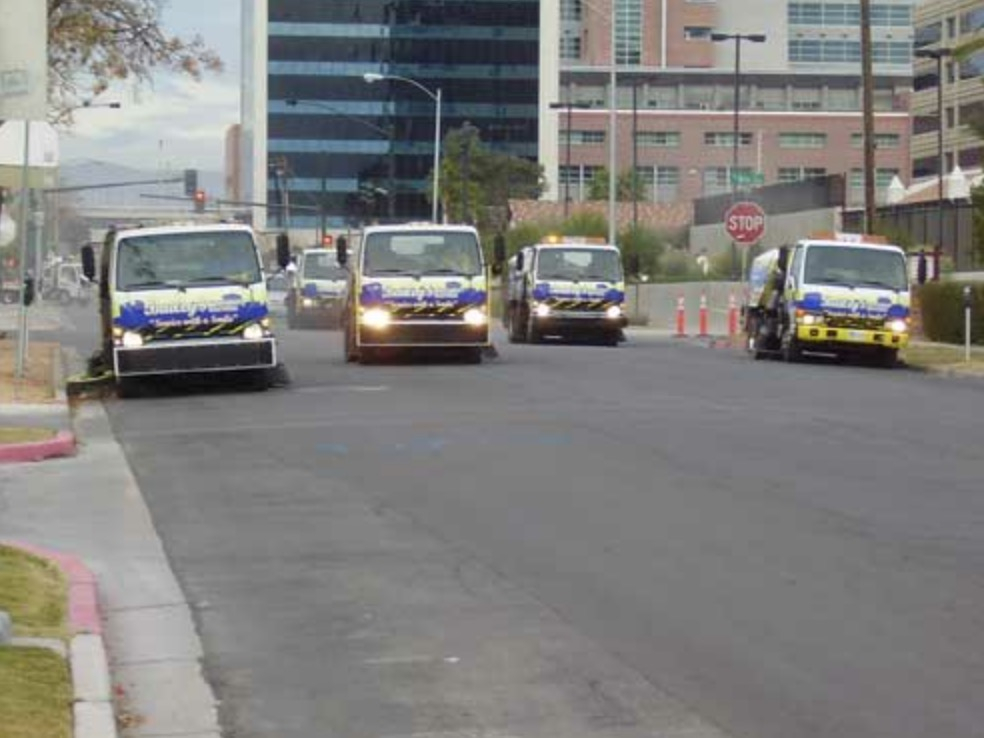 Four Bailey's sweeper trucks driving in convoy through downtown Las Vegas