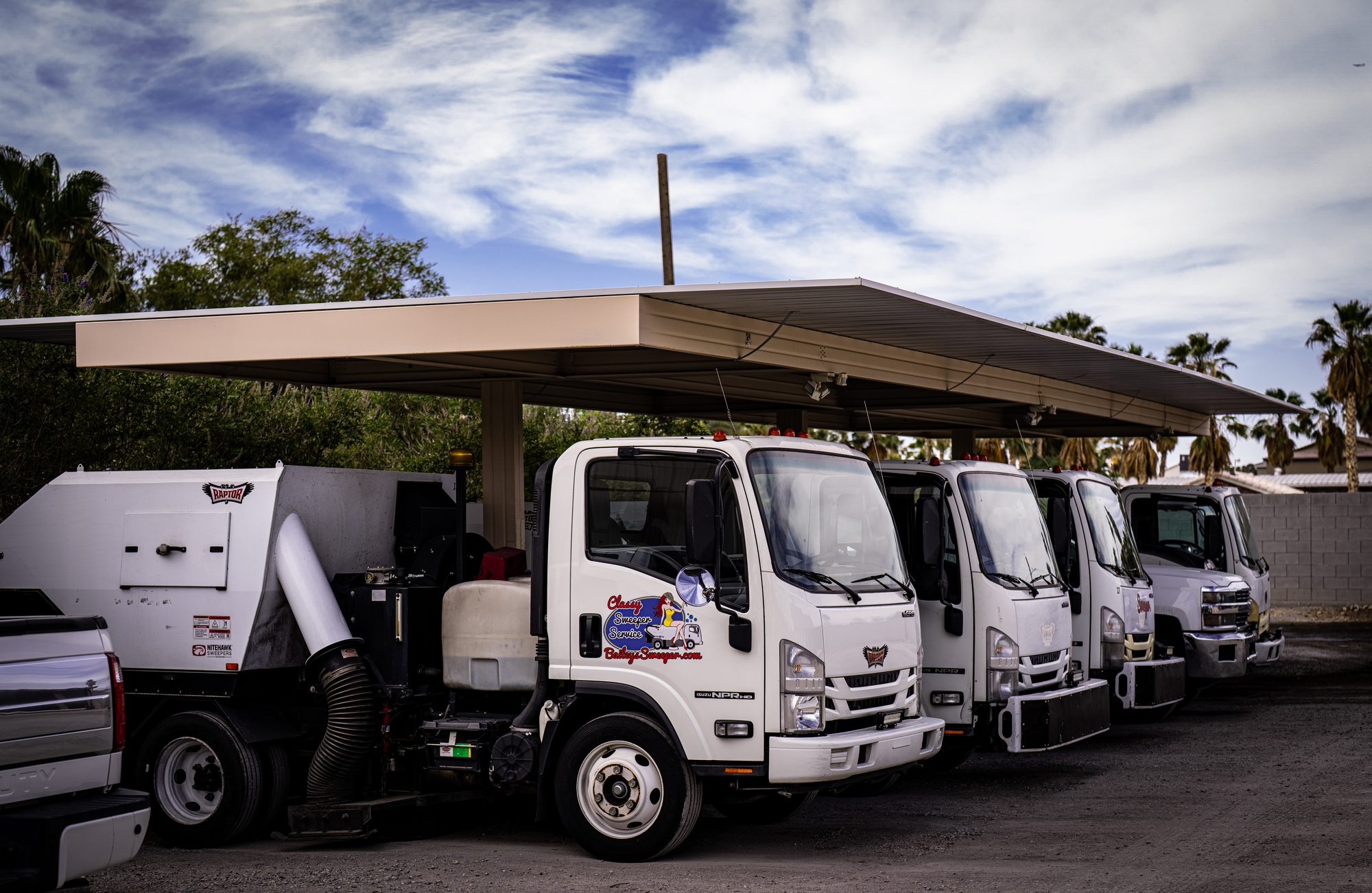 Bailey's fleet of Isuzu sweeper trucks lined up under the shade canopy at the yard