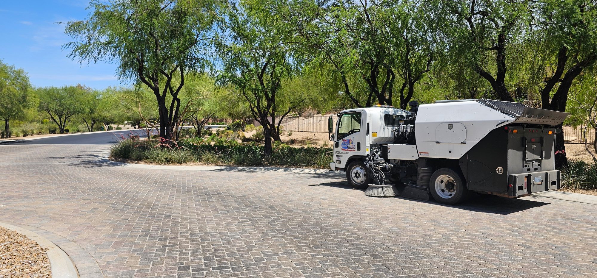 Bailey's sweeper working a paver-laid street through mature desert landscaping at The Ridges