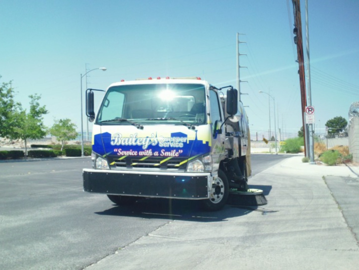 Front view of a Bailey's sweeper truck with the "Service with a Smile" tagline visible